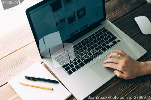 Image of Woman working with laptop placed on wooden desk