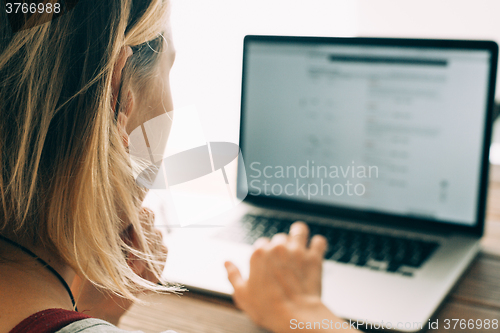 Image of Woman working with laptop placed on wooden desk