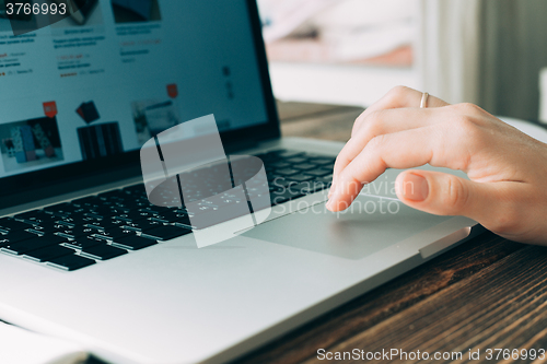 Image of Woman working with laptop placed on wooden desk