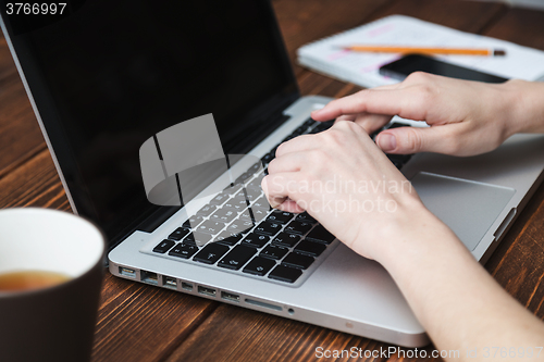 Image of Woman working with laptop placed on wooden desk