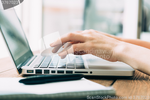 Image of Woman working with laptop placed on wooden desk