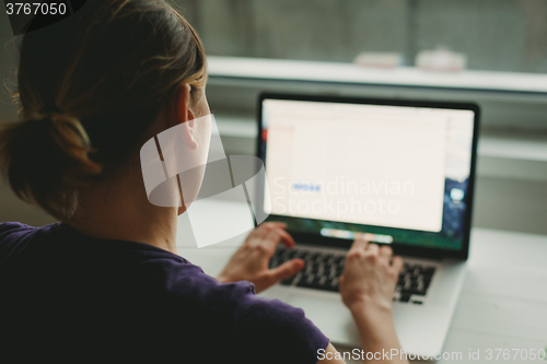 Image of Woman working with laptop placed on wooden desk