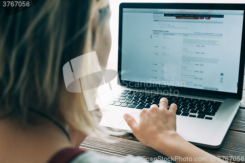 Image of Woman working with laptop placed on wooden desk