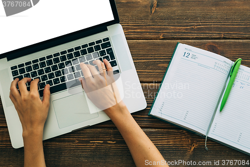 Image of Woman working with laptop placed on wooden desk