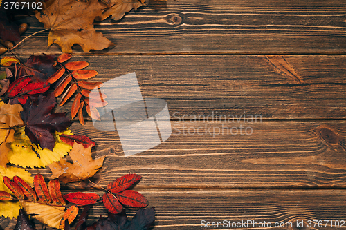 Image of Background with wooden table and autumnal leaves