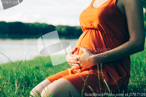 Image of Pregnant woman, holding in hands bouquet of daisy 
