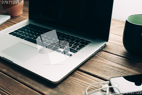 Image of Workplace with open laptop on modern wooden desk 