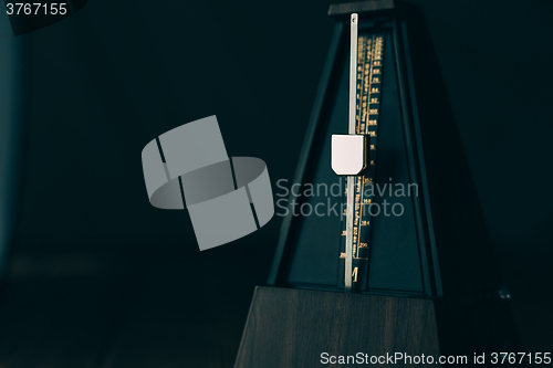 Image of Vintage metronome, on a dark background.