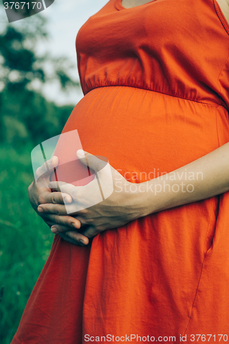 Image of Pregnant woman, holding in hands bouquet of daisy 