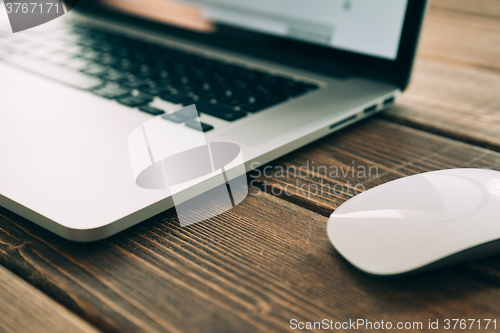 Image of Workplace with open laptop on modern wooden desk 