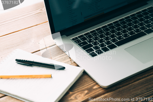 Image of Workplace with open laptop on modern wooden desk 