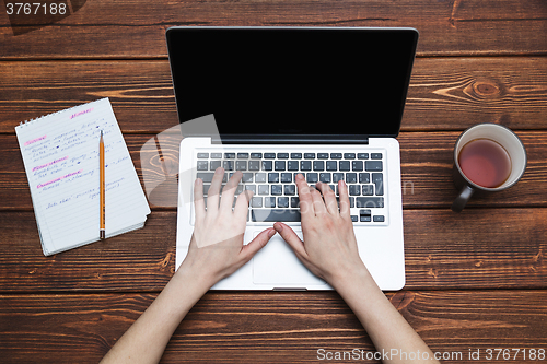 Image of Woman working with laptop placed on wooden desk