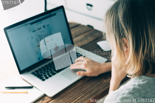 Image of Woman working with laptop placed on wooden desk