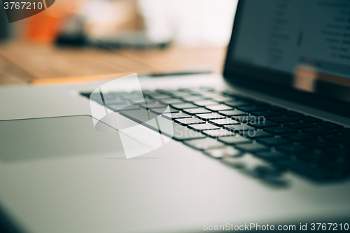 Image of Workplace with open laptop on modern wooden desk 