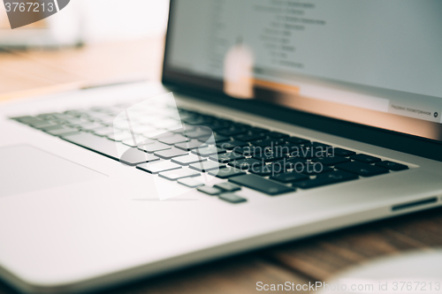 Image of Workplace with open laptop on modern wooden desk 