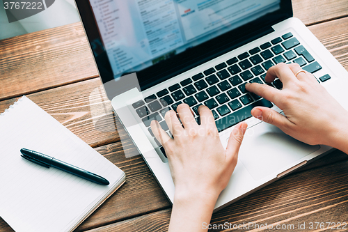 Image of Woman working with laptop placed on wooden desk