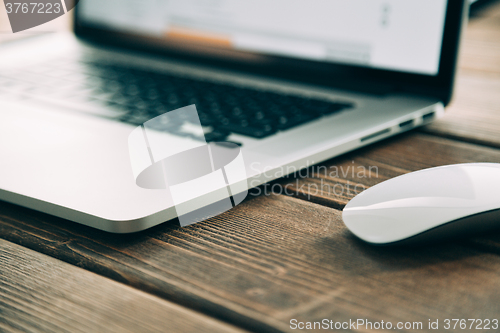 Image of Workplace with open laptop on modern wooden desk 