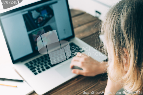 Image of Woman working with laptop placed on wooden desk