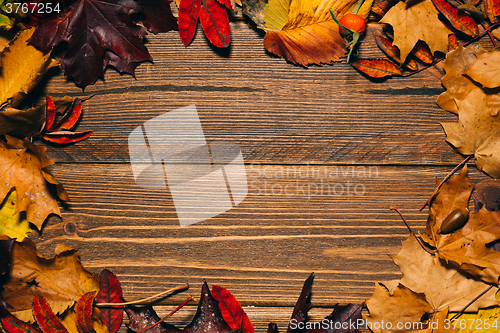 Image of Background with wooden table and autumnal leaves