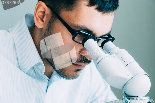 Image of Young male doctor viewing through microscope