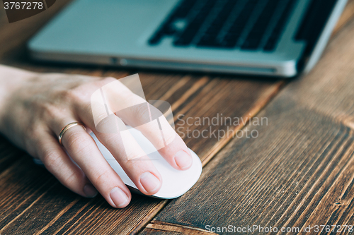 Image of Woman working with laptop placed on wooden desk