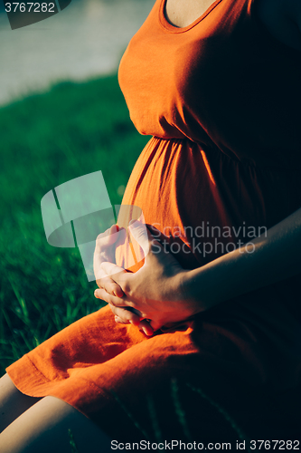 Image of Pregnant woman, holding in hands bouquet of daisy 