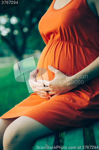 Image of Pregnant woman, holding in hands bouquet of daisy 