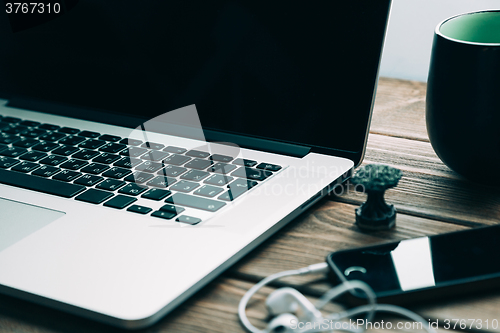 Image of Workplace with open laptop on modern wooden desk 