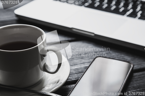 Image of Office table with notepad, computer and tea cup