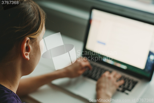 Image of Woman working with laptop placed on wooden desk