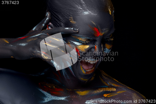 Image of Portrait of a young woman who is posing covered with  black paint 