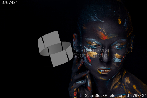 Image of Portrait of a young woman who is posing covered with  black paint 