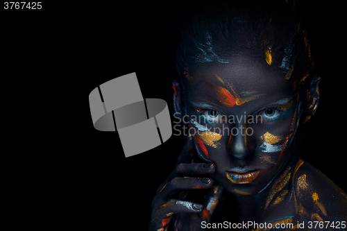 Image of Portrait of a young woman who is posing covered with  black paint 