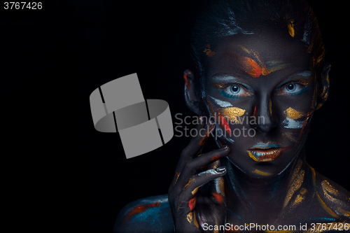 Image of Portrait of a young woman who is posing covered with  black paint 