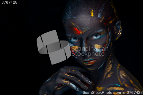 Image of Portrait of a young woman who is posing covered with  black paint 