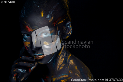 Image of Portrait of a young woman who is posing covered with  black paint 