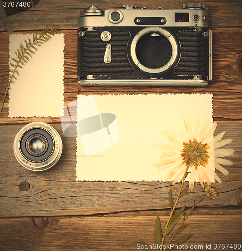 Image of mockup stillife with retro photo, camera, lens and pressed plant