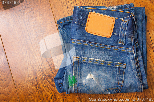 Image of old blue jeans with brown label on the belt smeared with green p
