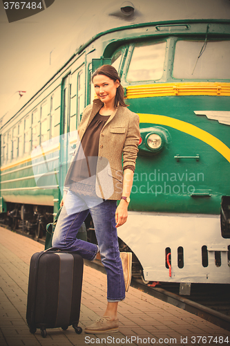 Image of beautiful middle-aged woman with luggage on a railway platform n