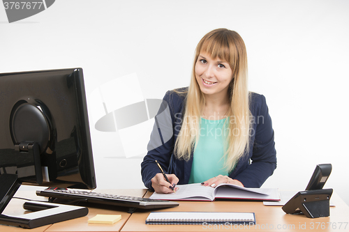 Image of Business woman wrote in a notebook and looked into the frame