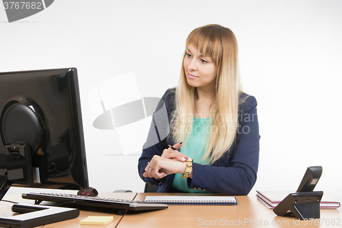 Image of Business woman checks the time on a computer with a wristwatch