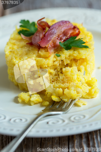 Image of Saffron risotto garnished with bacon and parsley.