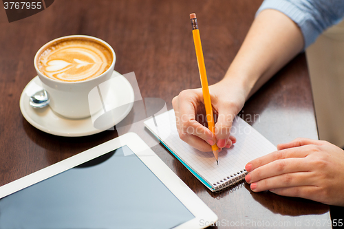 Image of close up of woman writing to notebook with pencil