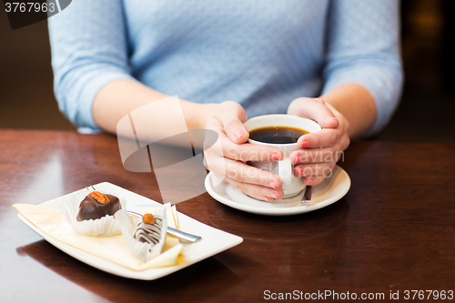 Image of close up of woman holding coffee cup and dessert