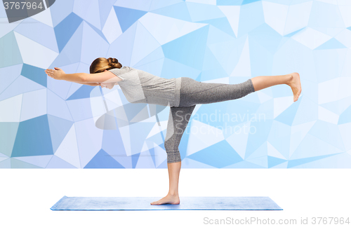 Image of woman making yoga warrior pose on mat