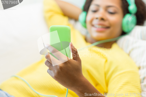 Image of happy african woman with smartphone and headphones