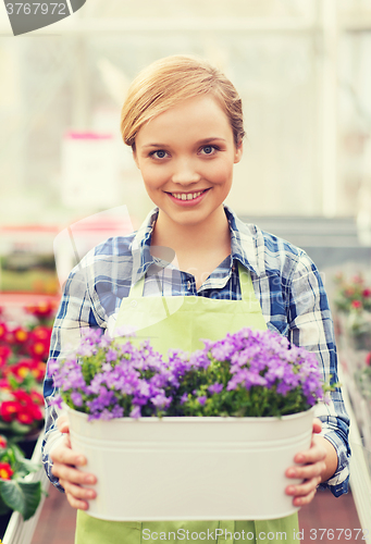 Image of happy woman holding flowers in greenhouse