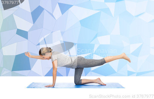 Image of woman making yoga in balancing table pose on mat