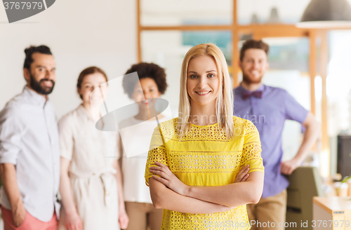 Image of happy young woman over creative team in office