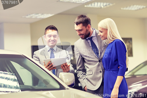 Image of happy couple with car dealer in auto show or salon